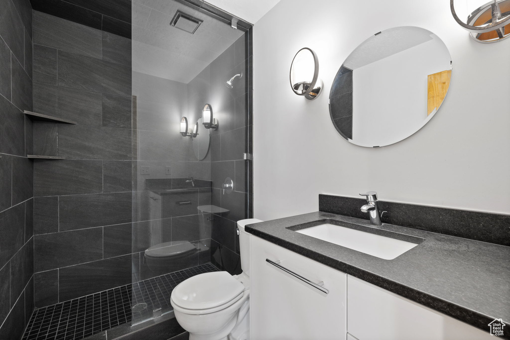 Bathroom with tiled shower, vanity, and toilet