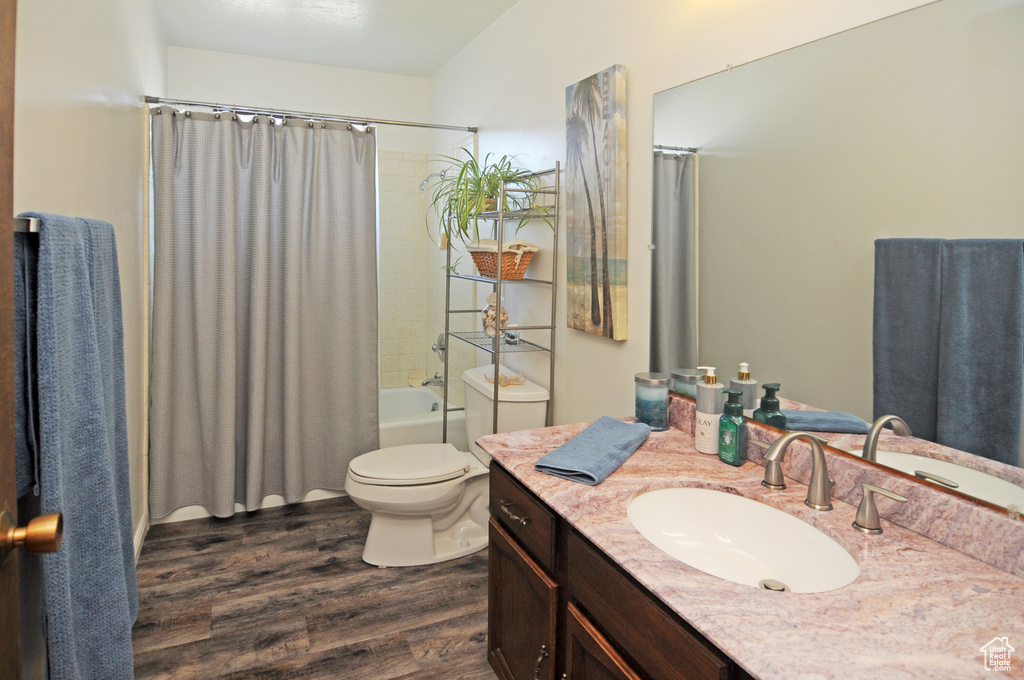 Full bathroom featuring toilet, hardwood / wood-style flooring, vanity, and shower / tub combo