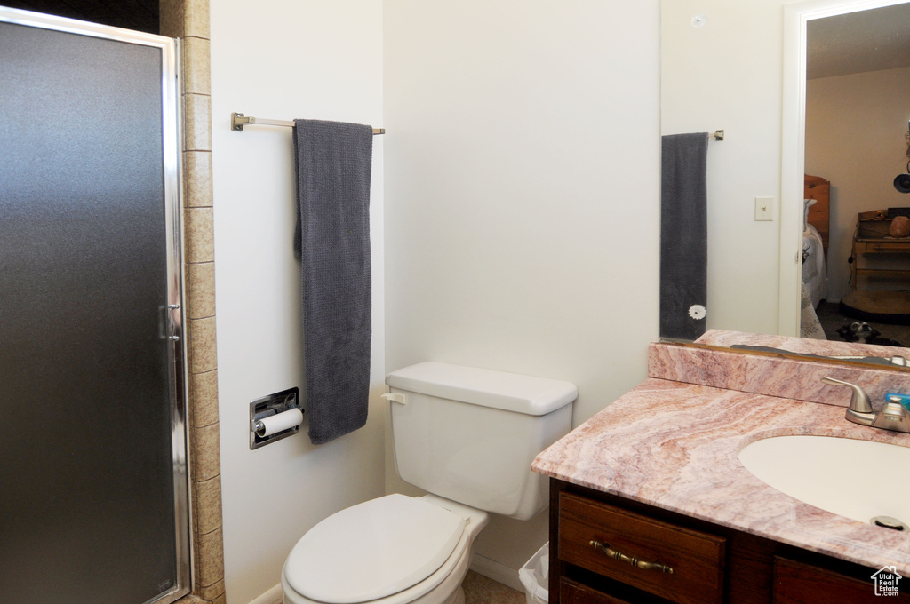 Bathroom with vanity, toilet, and a shower with shower door