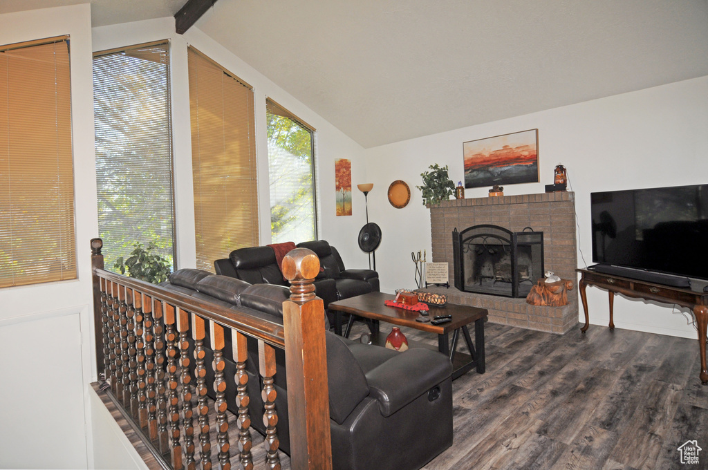 Living room featuring dark hardwood / wood-style flooring, vaulted ceiling with beams, and a fireplace