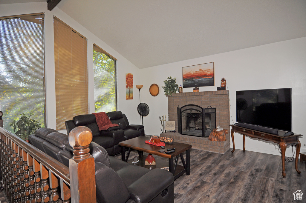 Living room featuring vaulted ceiling with beams, a fireplace, and dark hardwood / wood-style flooring