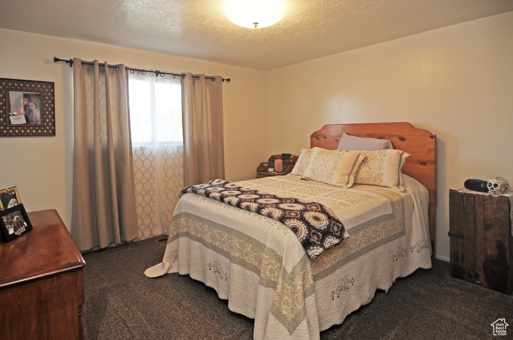 Bedroom featuring a textured ceiling and dark carpet