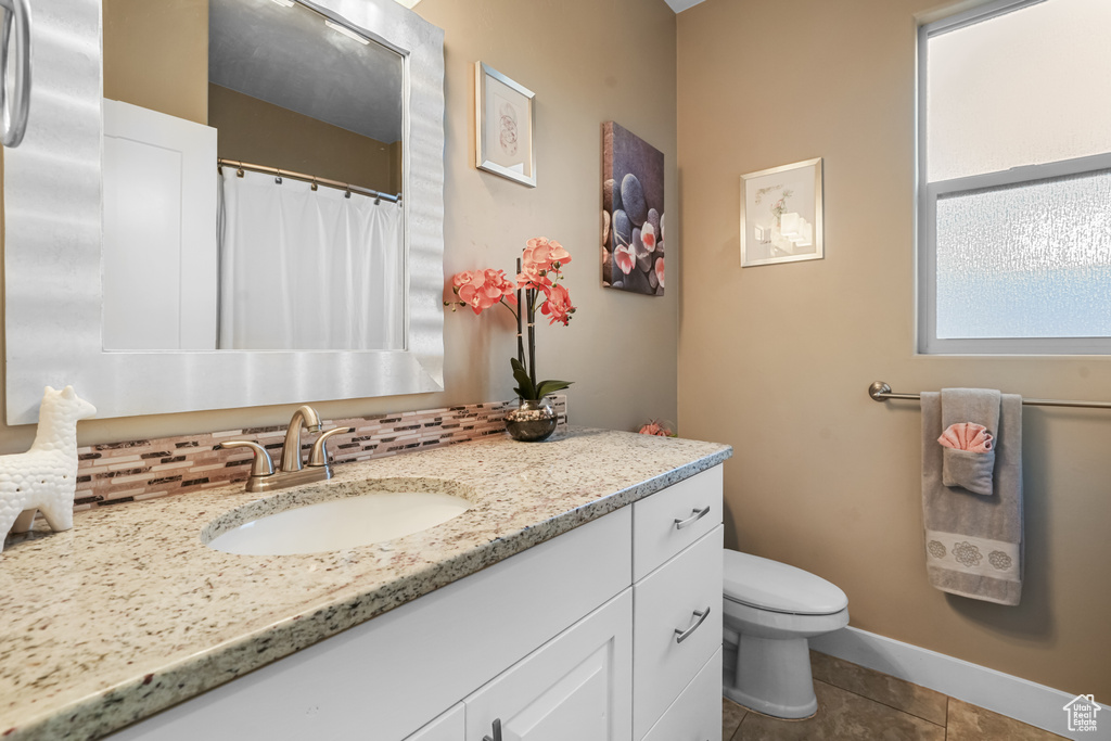 Bathroom featuring backsplash, vanity, toilet, and tile patterned floors