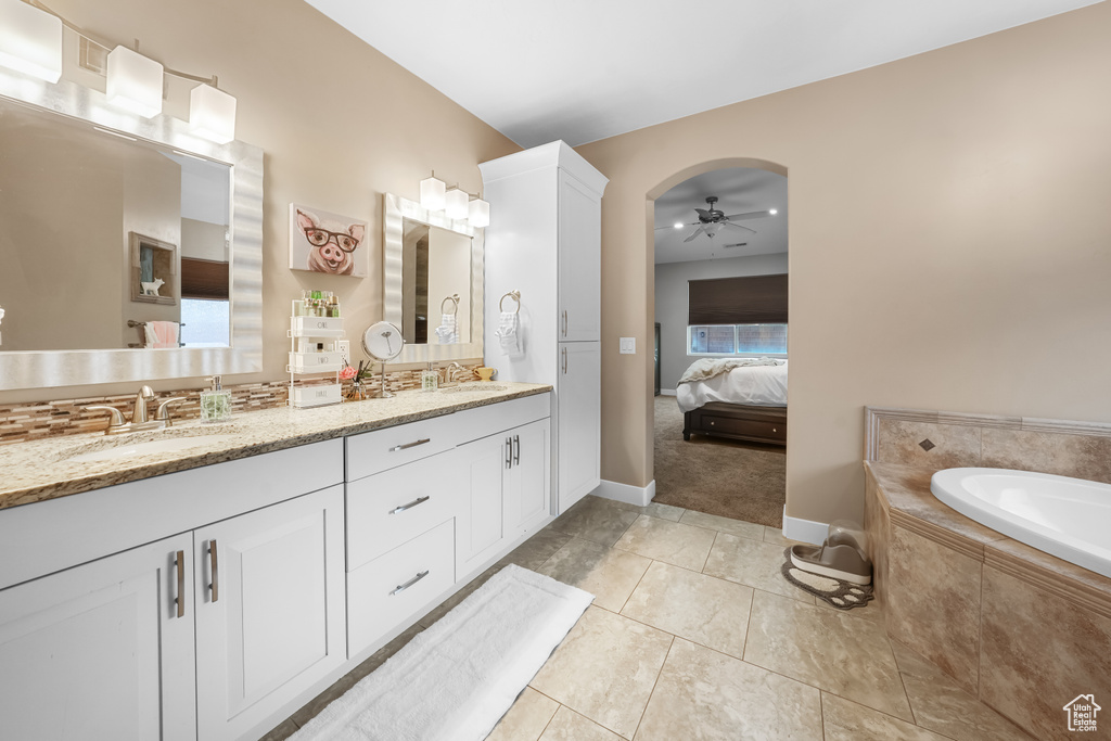 Bathroom featuring vanity, ceiling fan, tile patterned flooring, and tiled tub