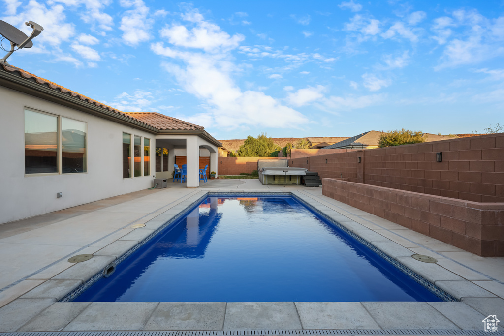 View of swimming pool featuring a hot tub and a patio area