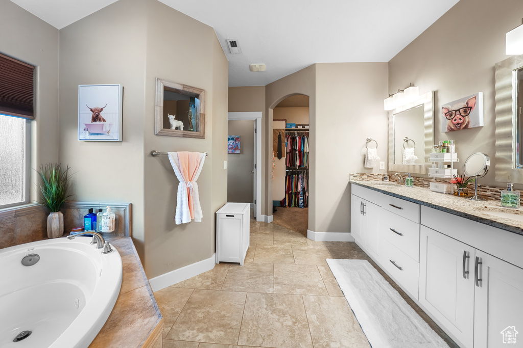 Bathroom with vanity and tiled bath