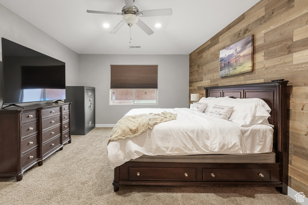 Bedroom with ceiling fan, light carpet, and wooden walls