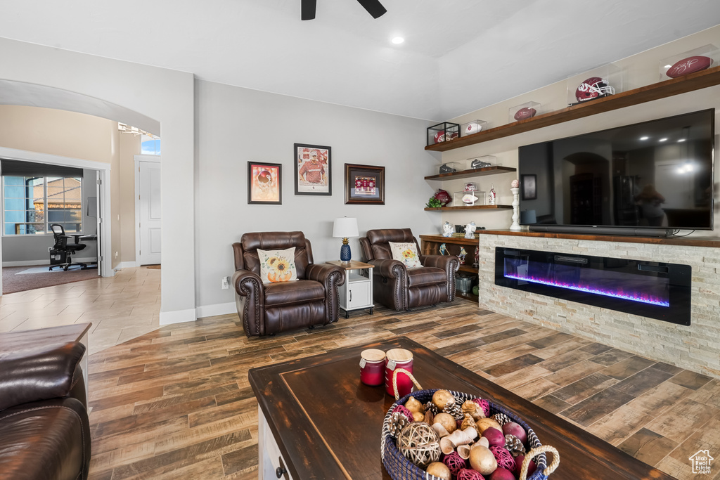 Living room featuring a fireplace, wood-type flooring, and ceiling fan