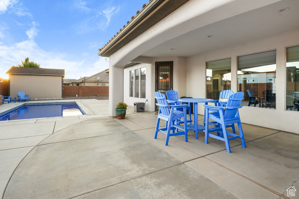 View of swimming pool with a storage shed and a patio area