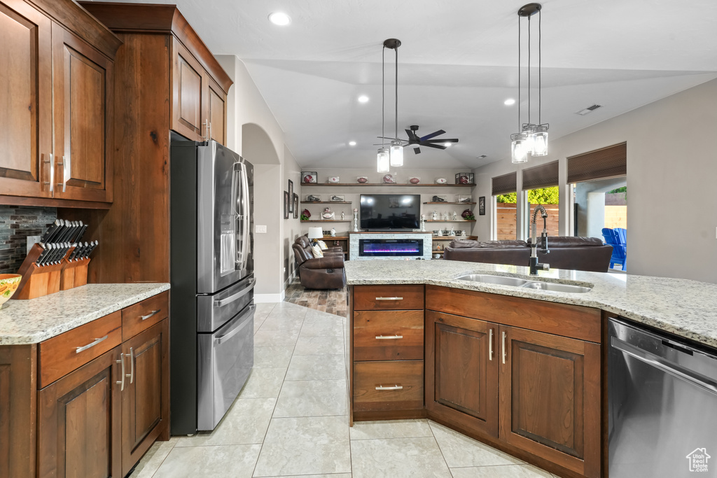 Kitchen with lofted ceiling, hanging light fixtures, sink, appliances with stainless steel finishes, and ceiling fan