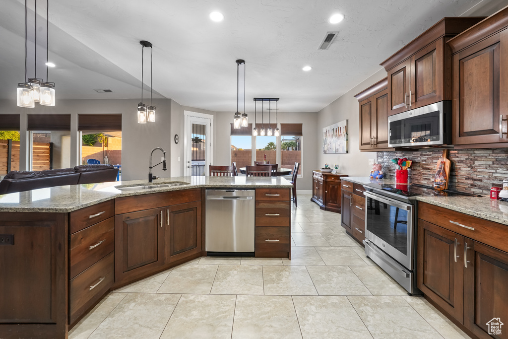 Kitchen with sink, a kitchen island with sink, decorative light fixtures, and stainless steel appliances