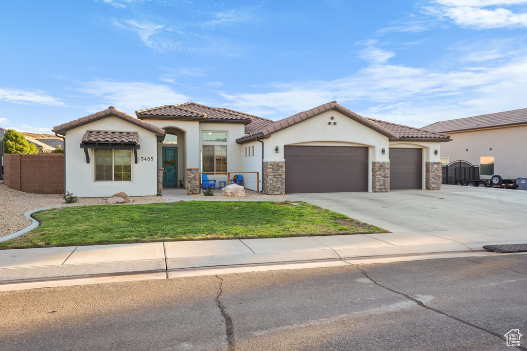 Mediterranean / spanish-style home featuring a front yard and a garage