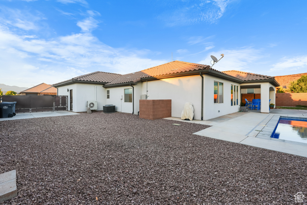 Rear view of house featuring a patio, central AC, and a fenced in pool