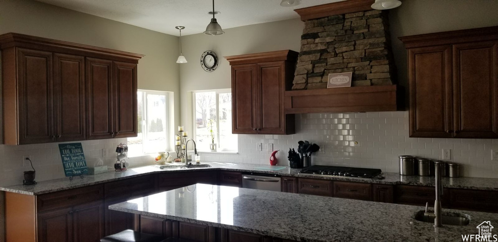 Kitchen with sink, stainless steel dishwasher, pendant lighting, gas cooktop, and decorative backsplash