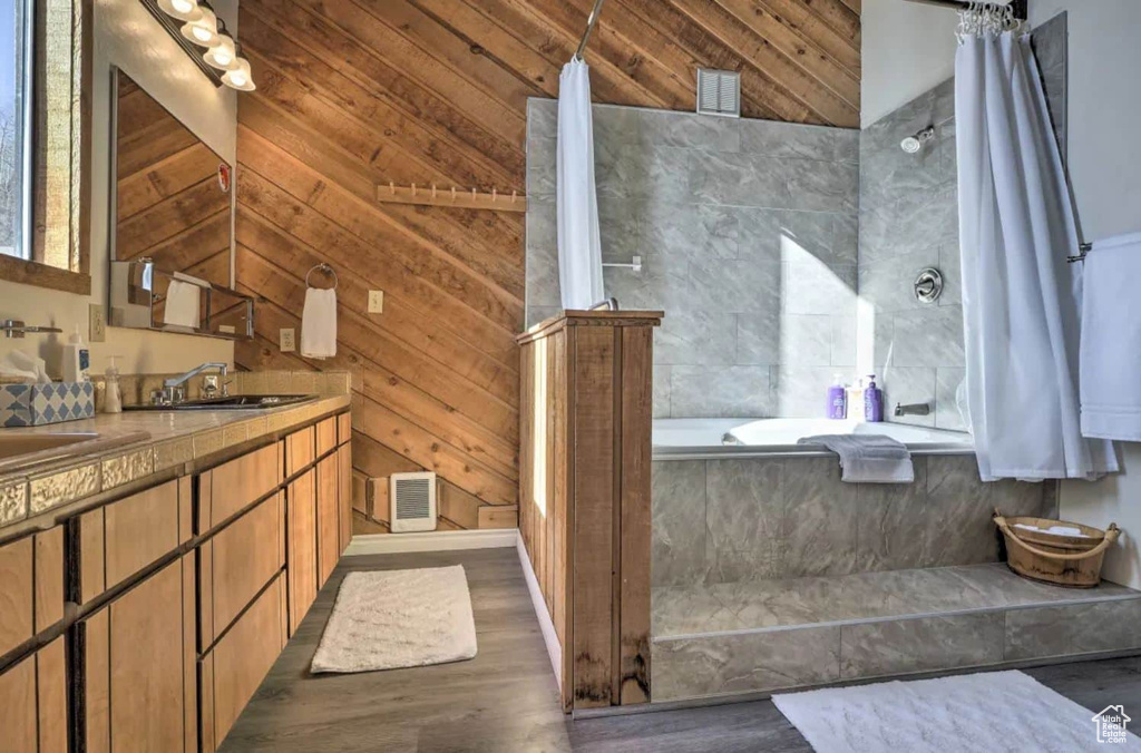 Bathroom featuring wood walls, wood-type flooring, plus walk in shower, vaulted ceiling, and vanity