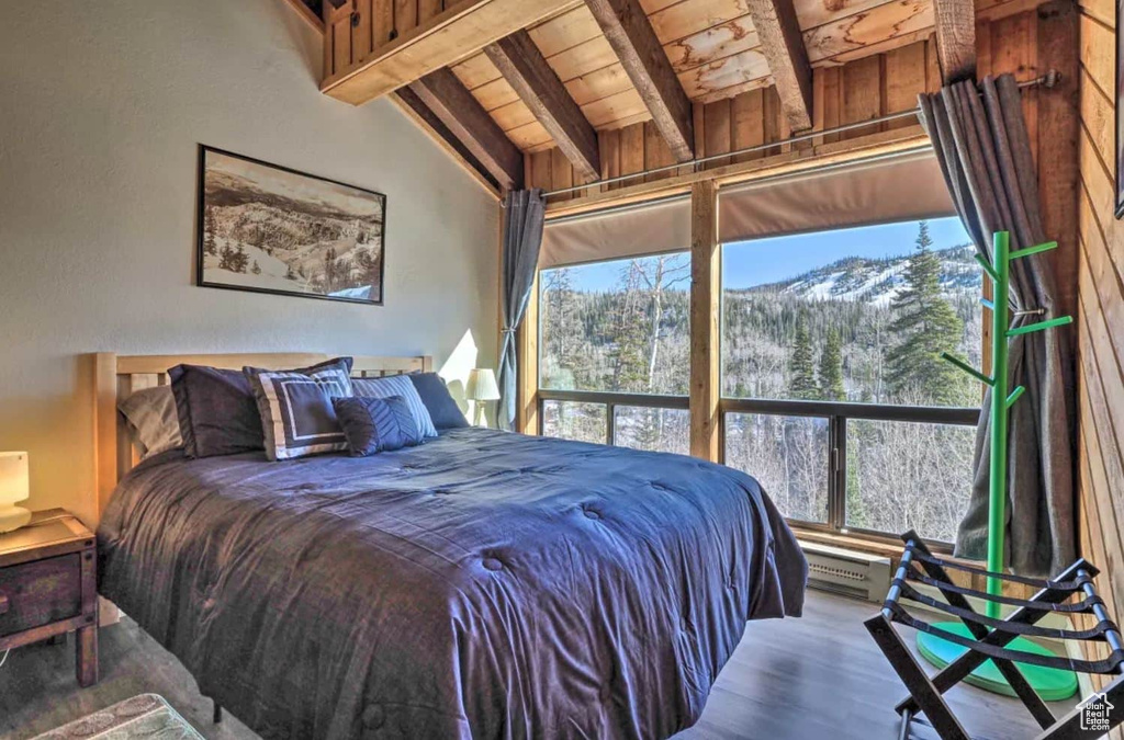 Bedroom with lofted ceiling with beams, a mountain view, hardwood / wood-style floors, and wooden ceiling