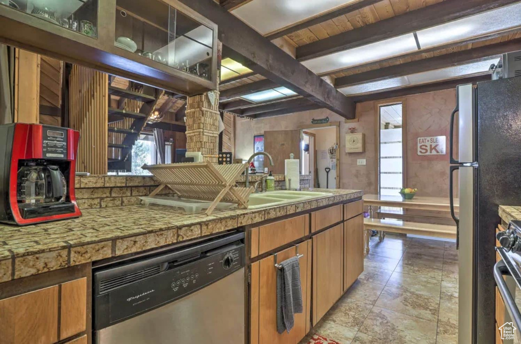 Kitchen with appliances with stainless steel finishes, beamed ceiling, and sink