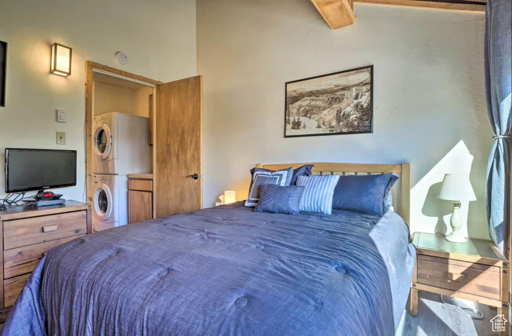 Bedroom with beam ceiling and stacked washer / dryer