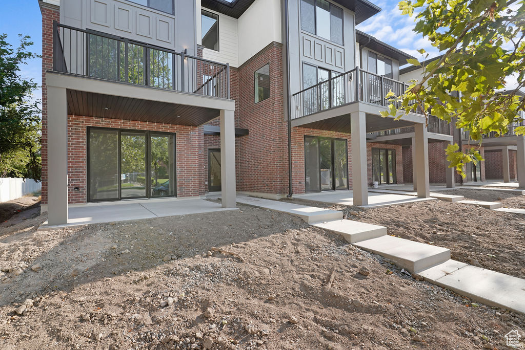 Back of property featuring a balcony and a patio