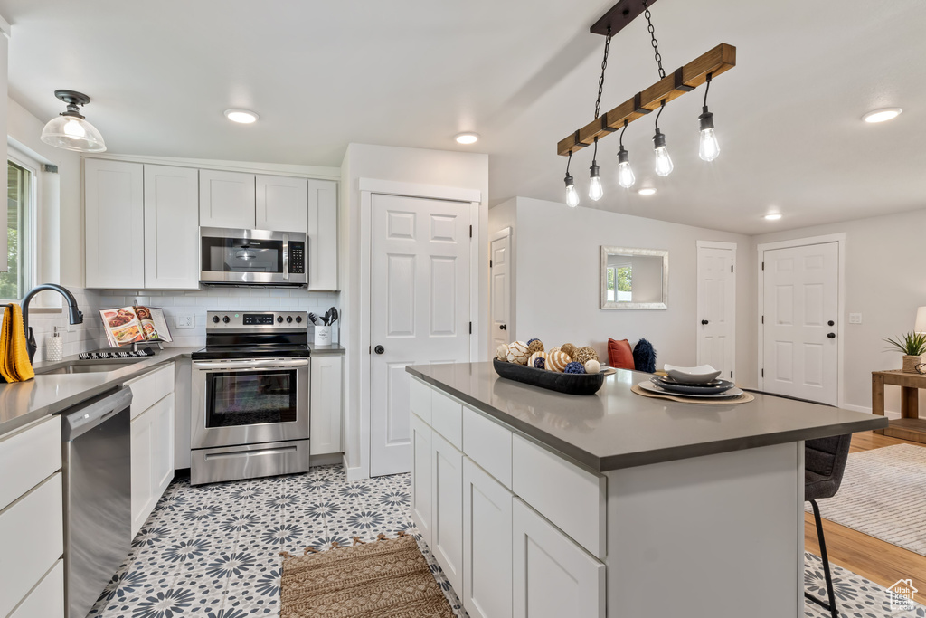 Kitchen featuring a center island, white cabinets, a healthy amount of sunlight, and stainless steel appliances