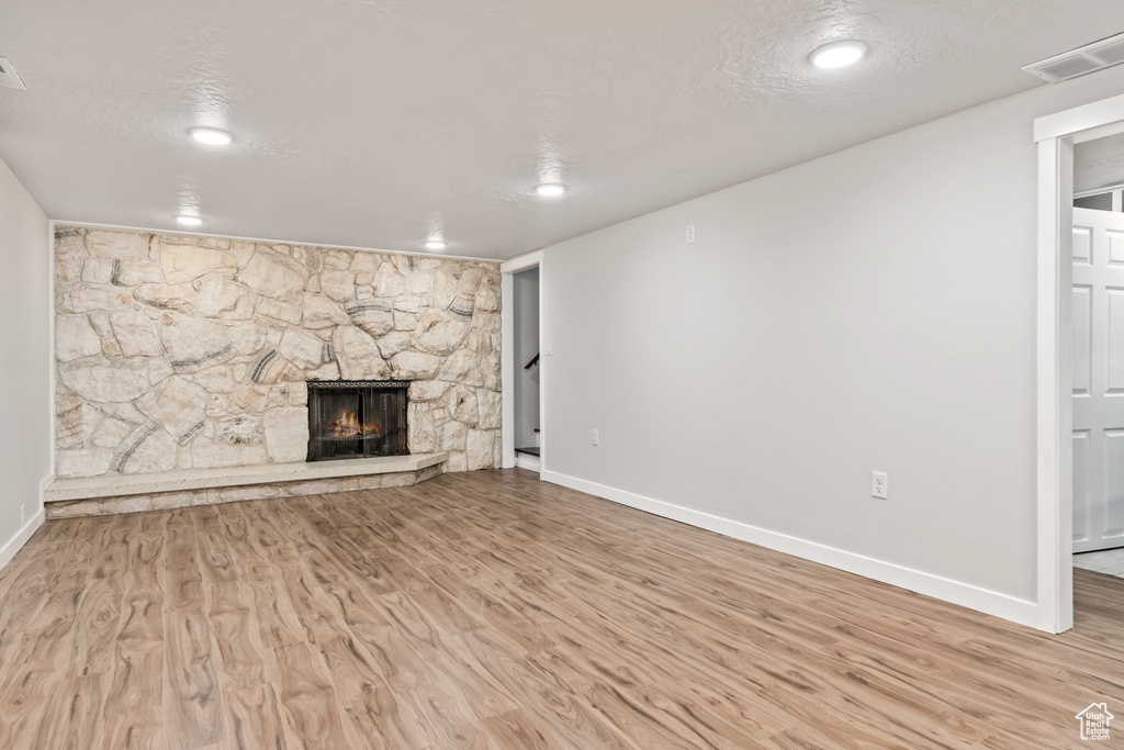 Unfurnished living room with a textured ceiling, light hardwood / wood-style flooring, and a fireplace