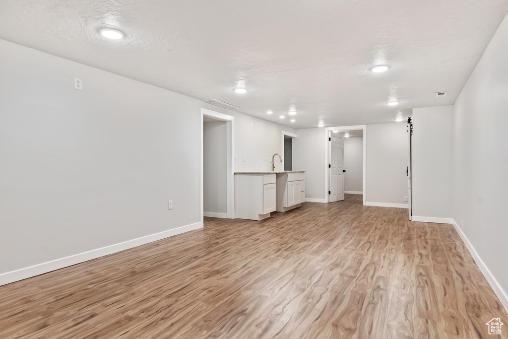 Unfurnished living room featuring light hardwood / wood-style floors, a textured ceiling, and sink