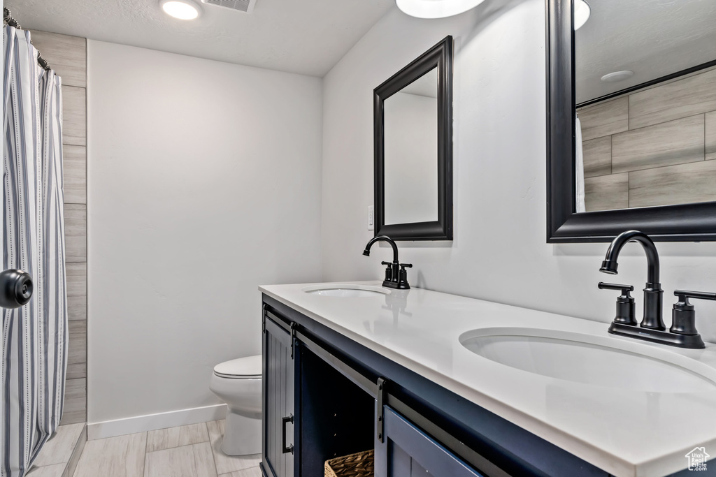 Bathroom with vanity, toilet, and tile patterned flooring