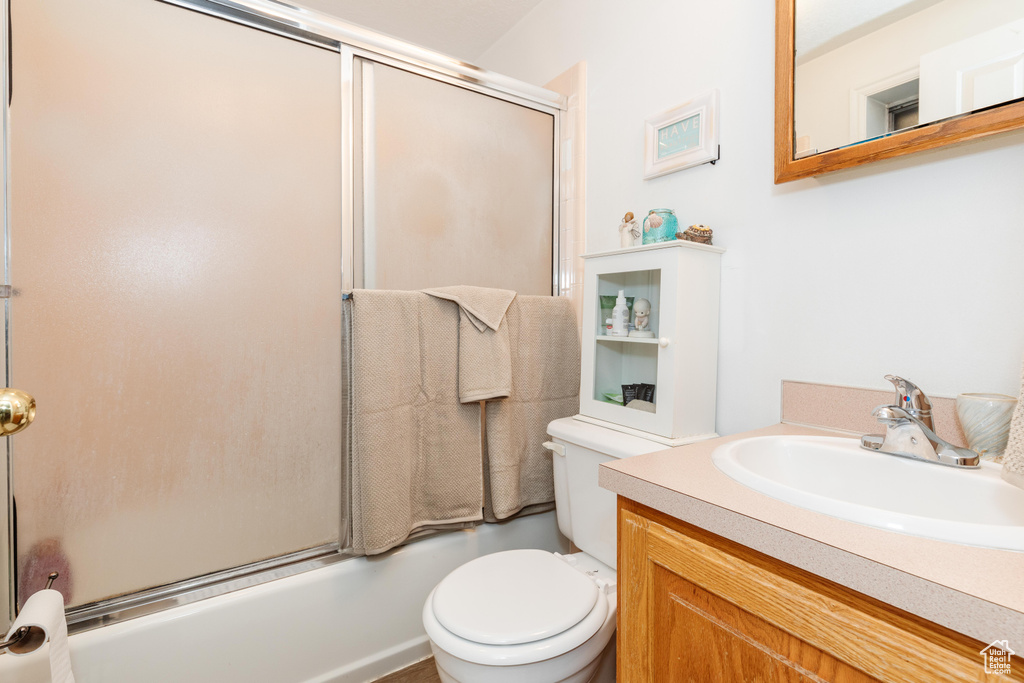 Full bathroom with vanity, combined bath / shower with glass door, and toilet