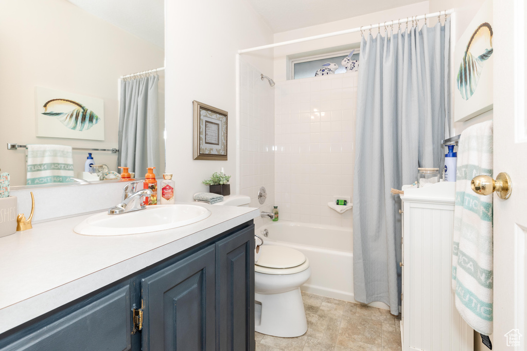 Full bathroom featuring vanity, shower / bath combo, and toilet