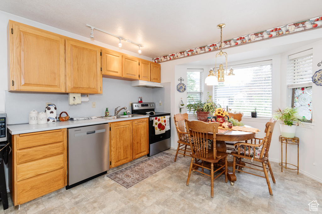 Kitchen with light brown cabinets, an inviting chandelier, decorative light fixtures, and stainless steel appliances