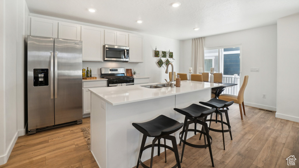 Kitchen featuring white cabinetry, appliances with stainless steel finishes, sink, and a kitchen island with sink