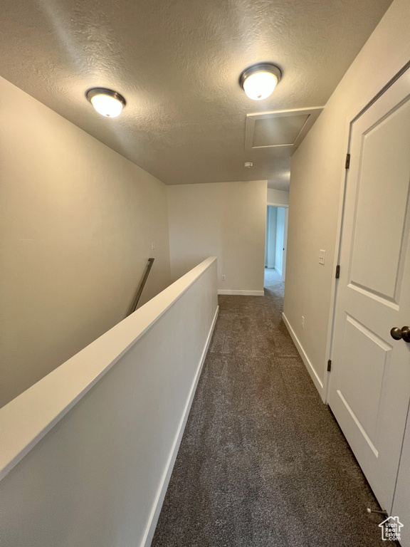 Corridor with dark carpet and a textured ceiling