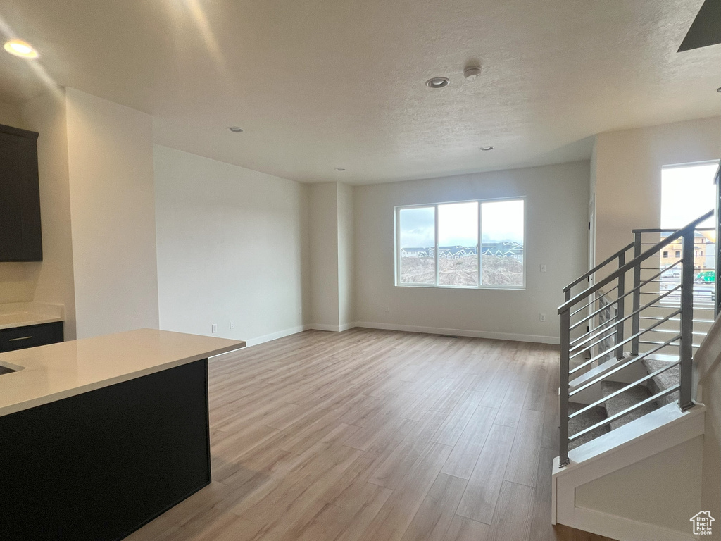 Unfurnished living room featuring a textured ceiling and light wood-type flooring