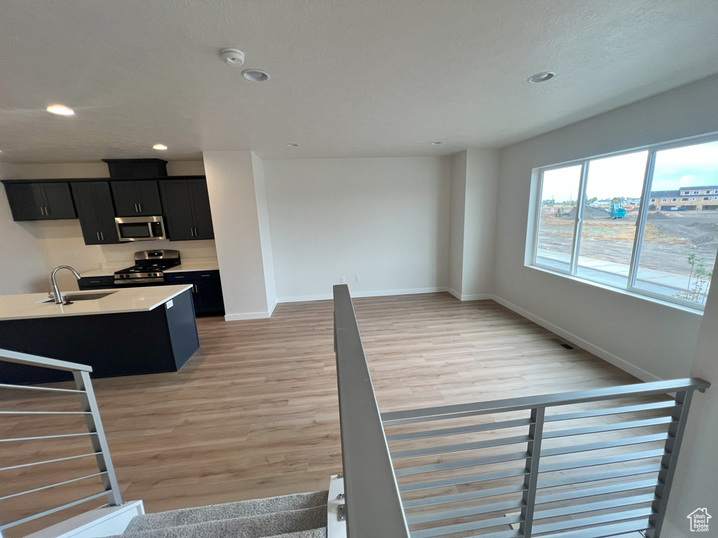 Interior space with appliances with stainless steel finishes, light hardwood / wood-style flooring, sink, and a kitchen island