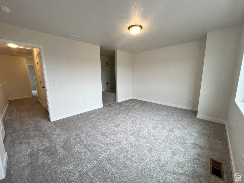 Empty room with a textured ceiling and dark carpet