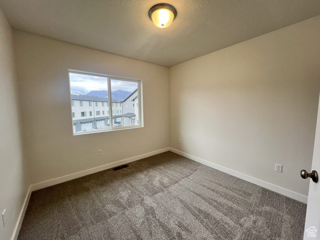 Empty room with carpet and a textured ceiling