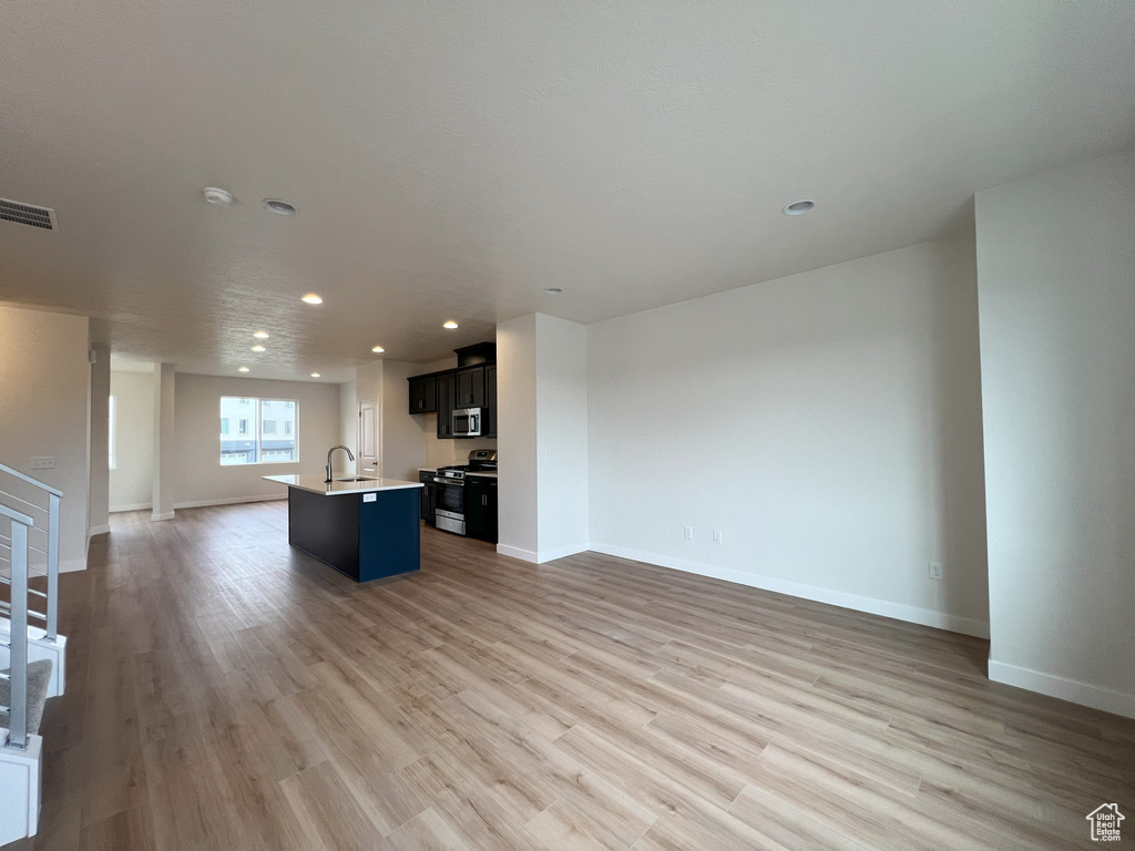 Kitchen featuring appliances with stainless steel finishes, hardwood / wood-style floors, sink, and a center island with sink