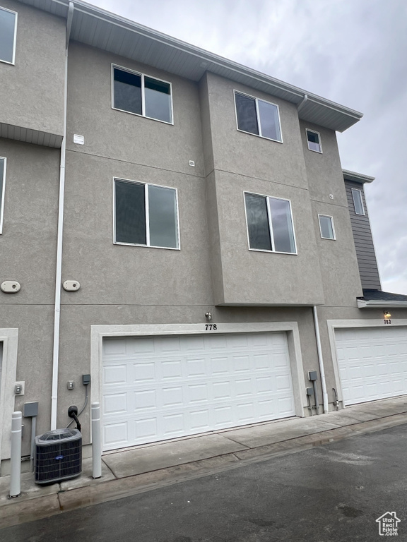 Rear view of house with central AC and a garage