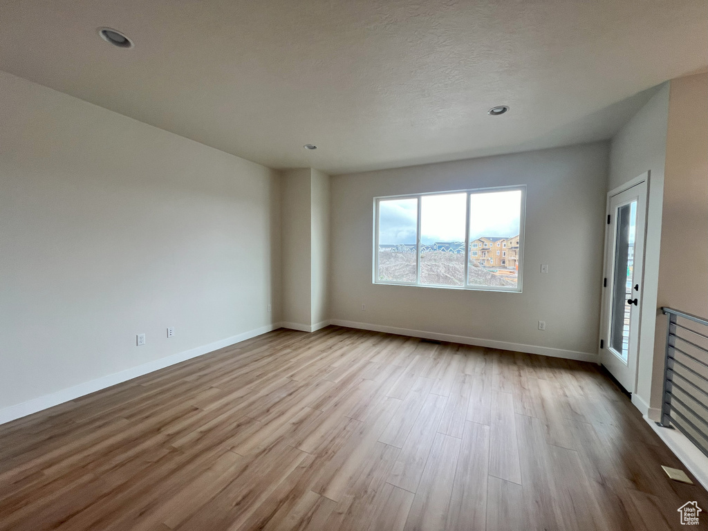 Empty room with a textured ceiling and light wood-type flooring