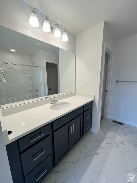 Bathroom with vanity, a textured ceiling, and walk in shower