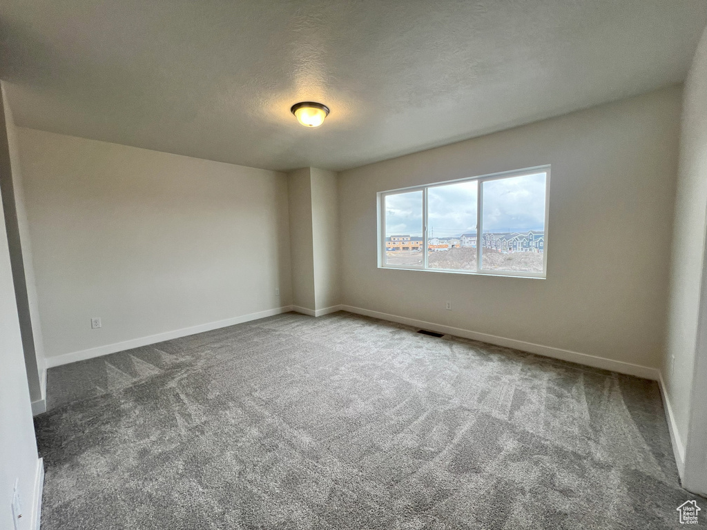 Spare room with a textured ceiling and dark carpet