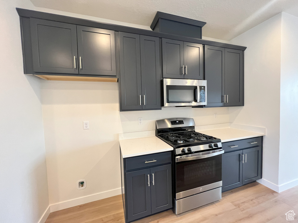 Kitchen with a textured ceiling, stainless steel appliances, and light wood-type flooring