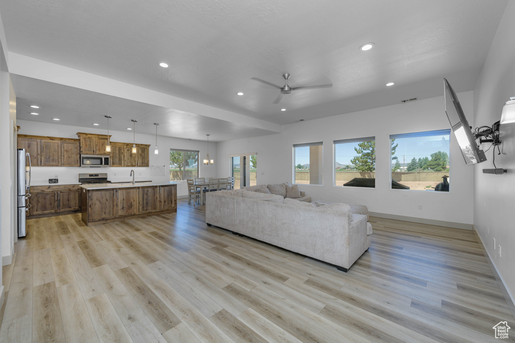 Living room featuring ceiling fan, sink, and light wood-type flooring