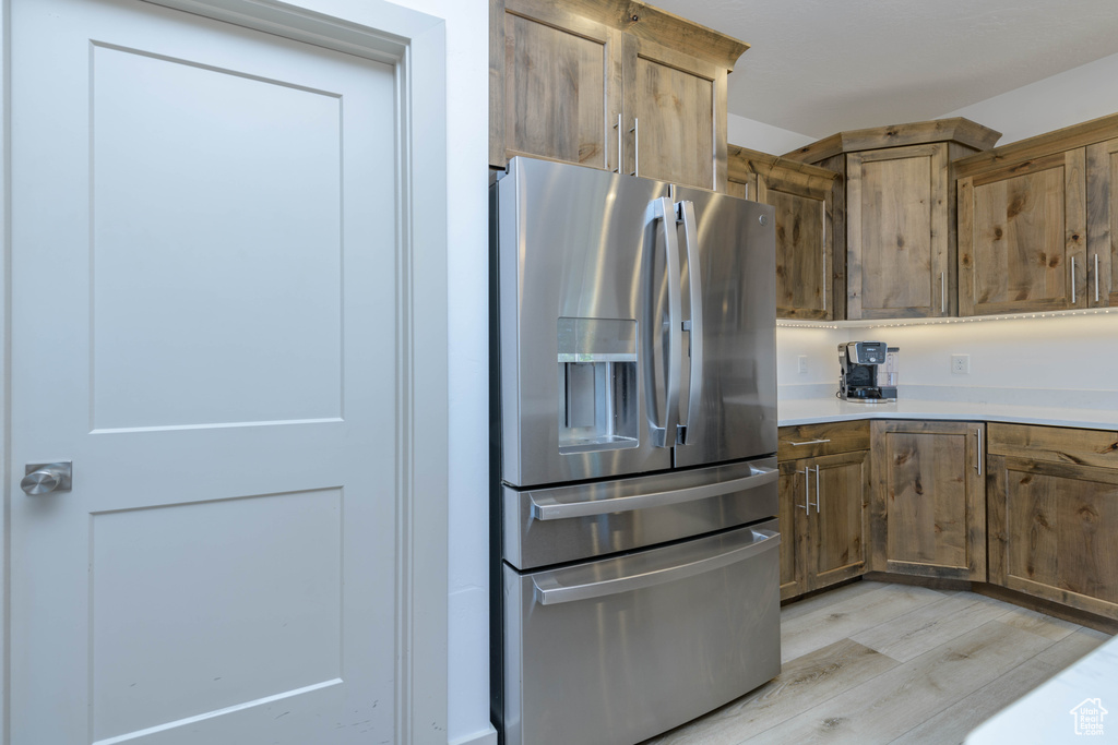 Kitchen with light hardwood / wood-style flooring and stainless steel fridge with ice dispenser