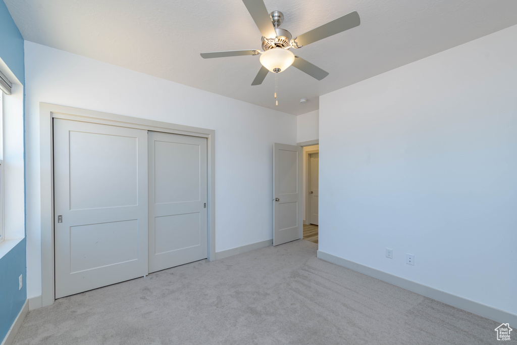 Unfurnished bedroom with light carpet, a closet, and ceiling fan