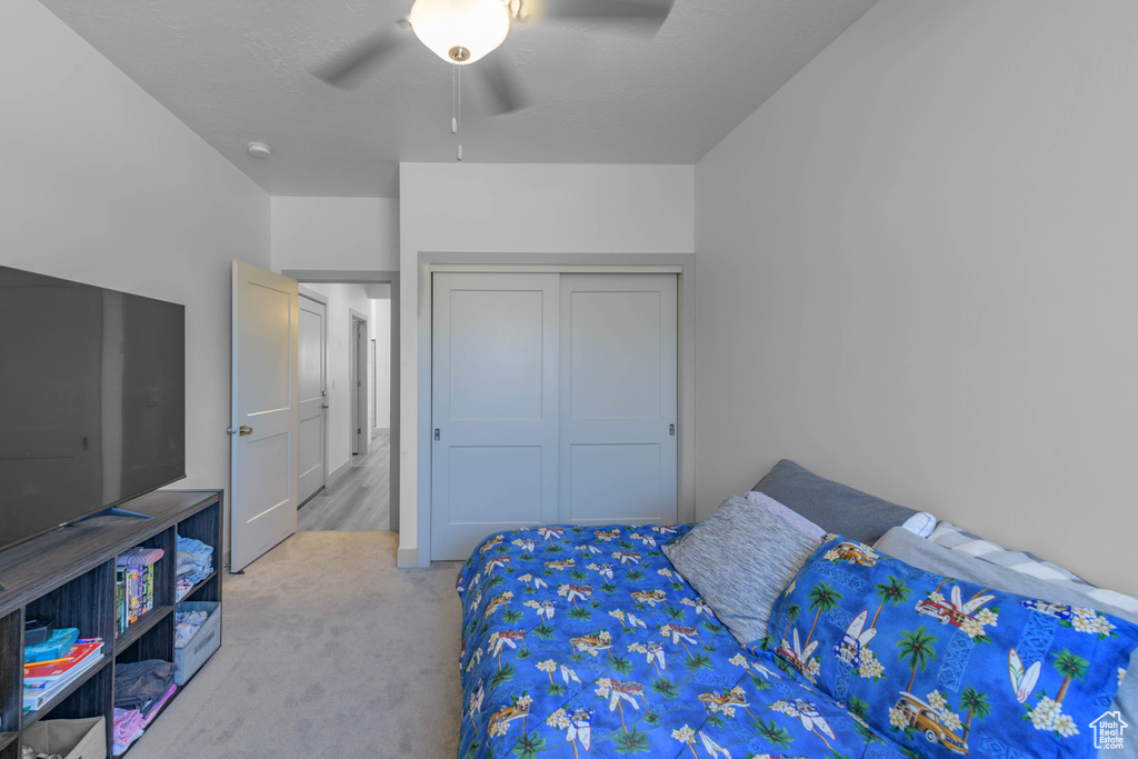 Bedroom featuring a closet, light colored carpet, and ceiling fan