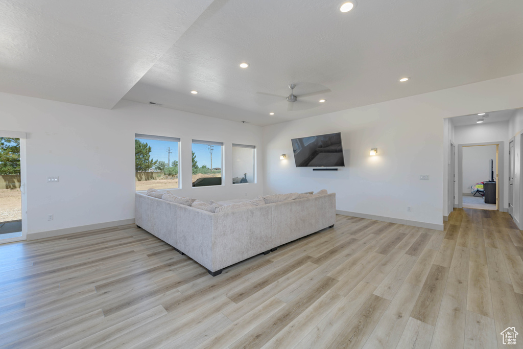 Unfurnished living room featuring ceiling fan and light wood-type flooring