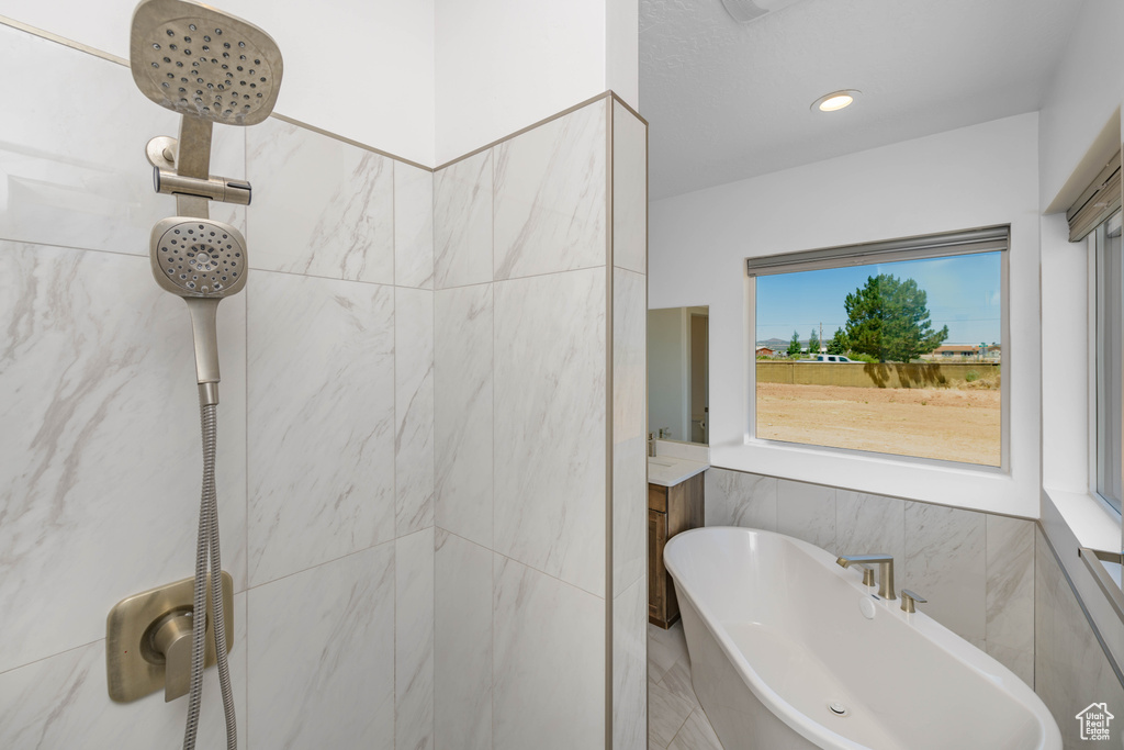 Bathroom featuring tile walls and separate shower and tub