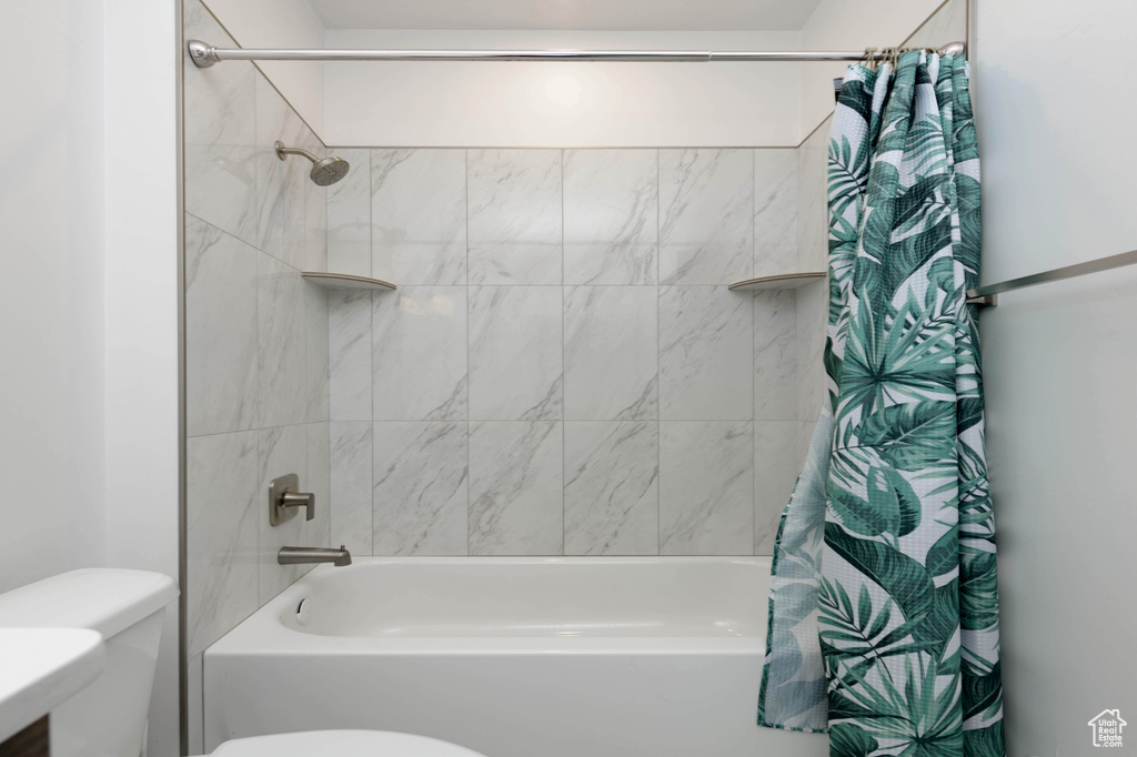 Bathroom featuring toilet and shower / bathtub combination with curtain