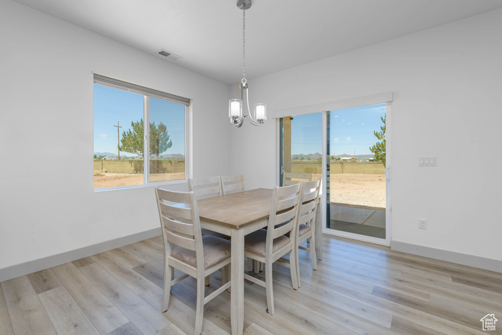 Dining room with light hardwood / wood-style flooring and a notable chandelier